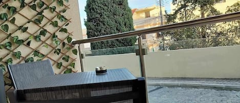 A black metal chair with a mesh backrest on an outdoor balcony.