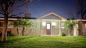 Una casa de dos pisos con fachada de piedra, un porche delantero y un césped bien cuidado.