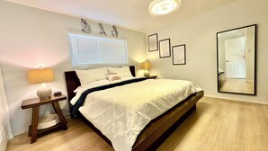 Un dormitorio con una cama grande, mesitas de noche, una lámpara, un espejo y obras de arte en la pared.