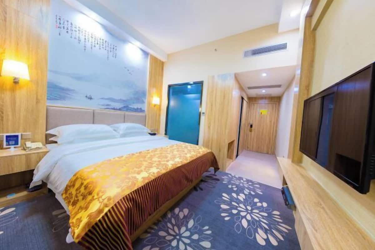 Une chambre d’hôtel équipée d’un lit, d’une télévision, d’un bureau et d’un mur orné d’une fresque.
