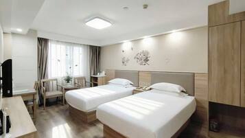 A hotel room with two beds, a desk, a chair, a small table, and a wardrobe.