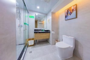 Un baño moderno con cabina de ducha de vidrio, tocador de madera y un inodoro blanco.