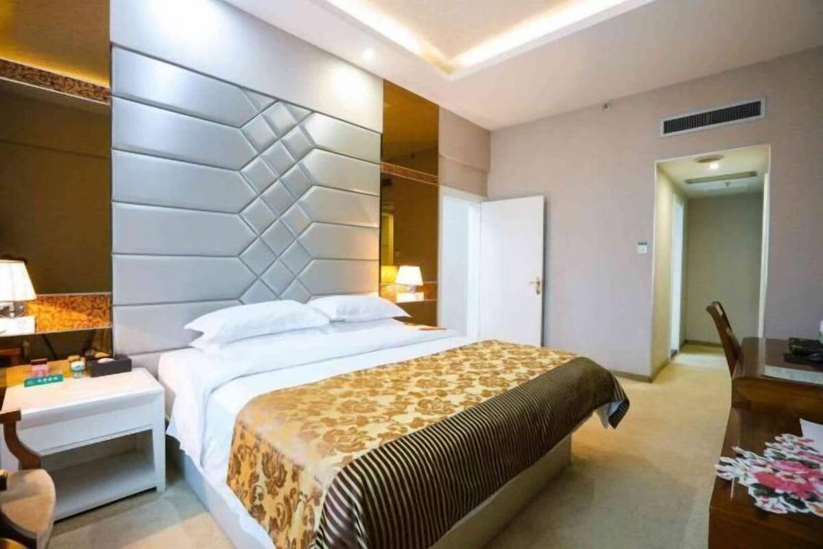 Une chambre d’hôtel avec un lit, une table de chevet, une lampe et un miroir.