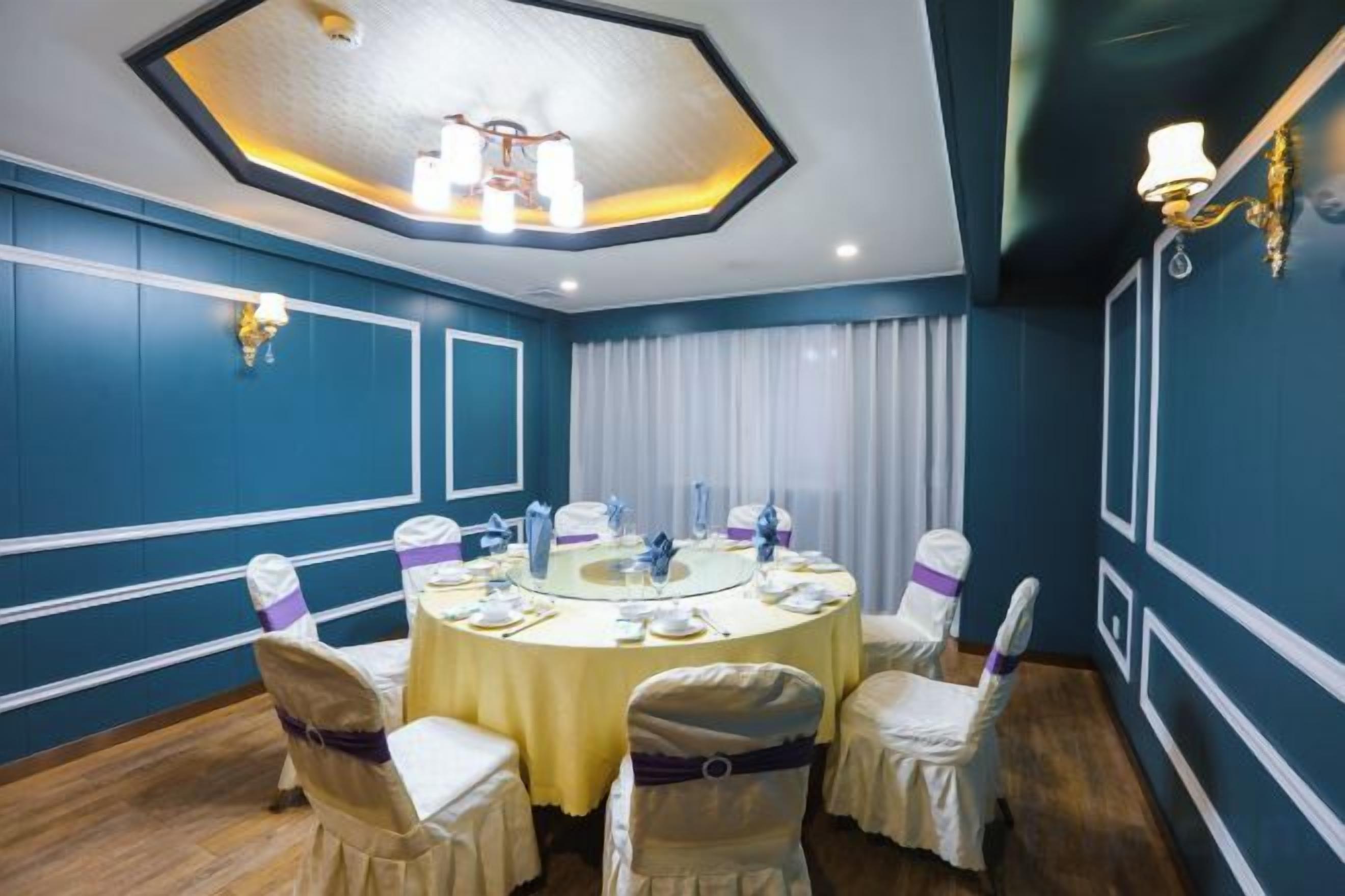 A conference room with a round table, chairs, and a chandelier.