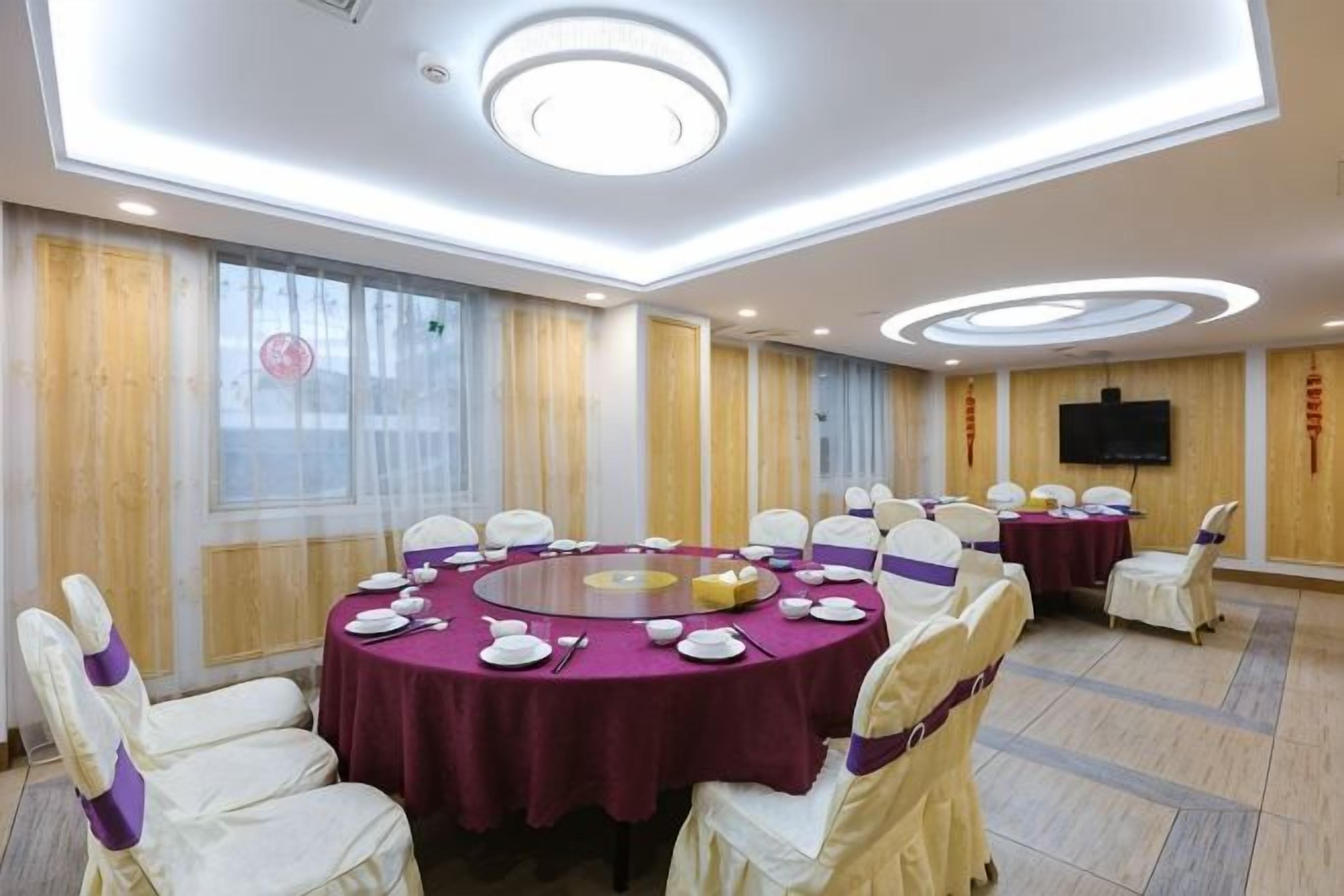 Un salón de conferencias con mesas redondas, sillas y una pantalla de televisión.