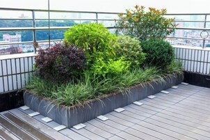 Un jardín en la azotea con diversas plantas y una terraza de madera.