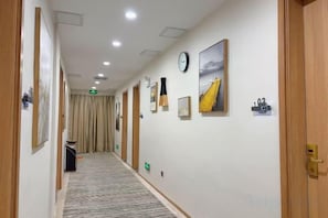 A hotel corridor with framed pictures on the walls, a clock, and a number sign. - GreenTree Liaocheng Yanggu Huangshan Road Shizilou (Yanggu)