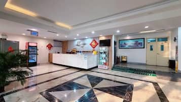 Un vestíbulo de hotel con mostrador de recepción, pantalla digital y piso estampado.