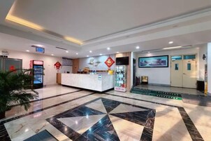 Un vestíbulo de hotel con mostrador de recepción, pantalla digital y piso estampado.