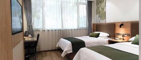 A hotel room with two beds, a desk, a chair, a window with curtains, and a wall-mounted lamp.