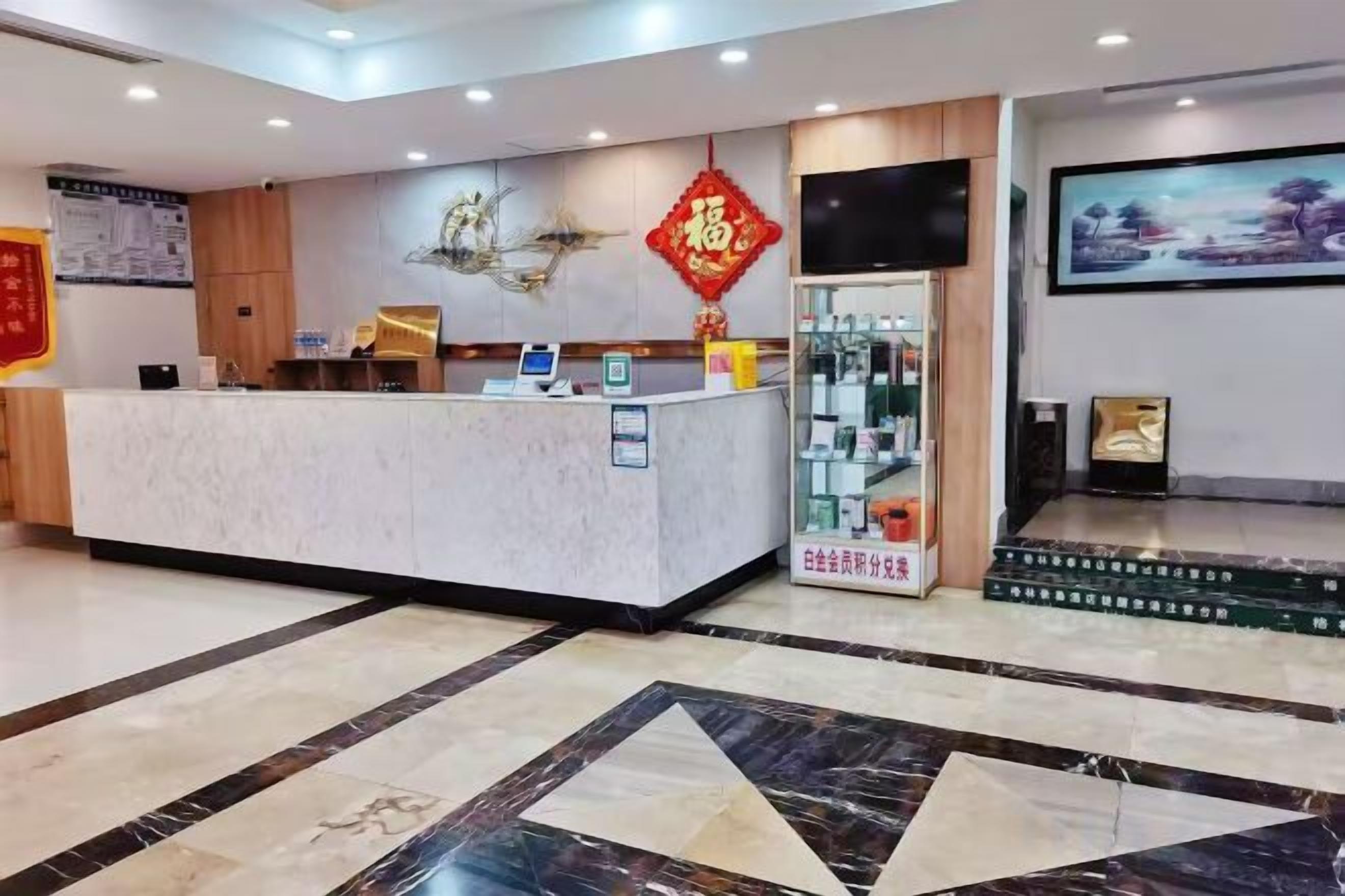 A hotel reception area with a marble counter, a television, and a framed artwork on the wall.