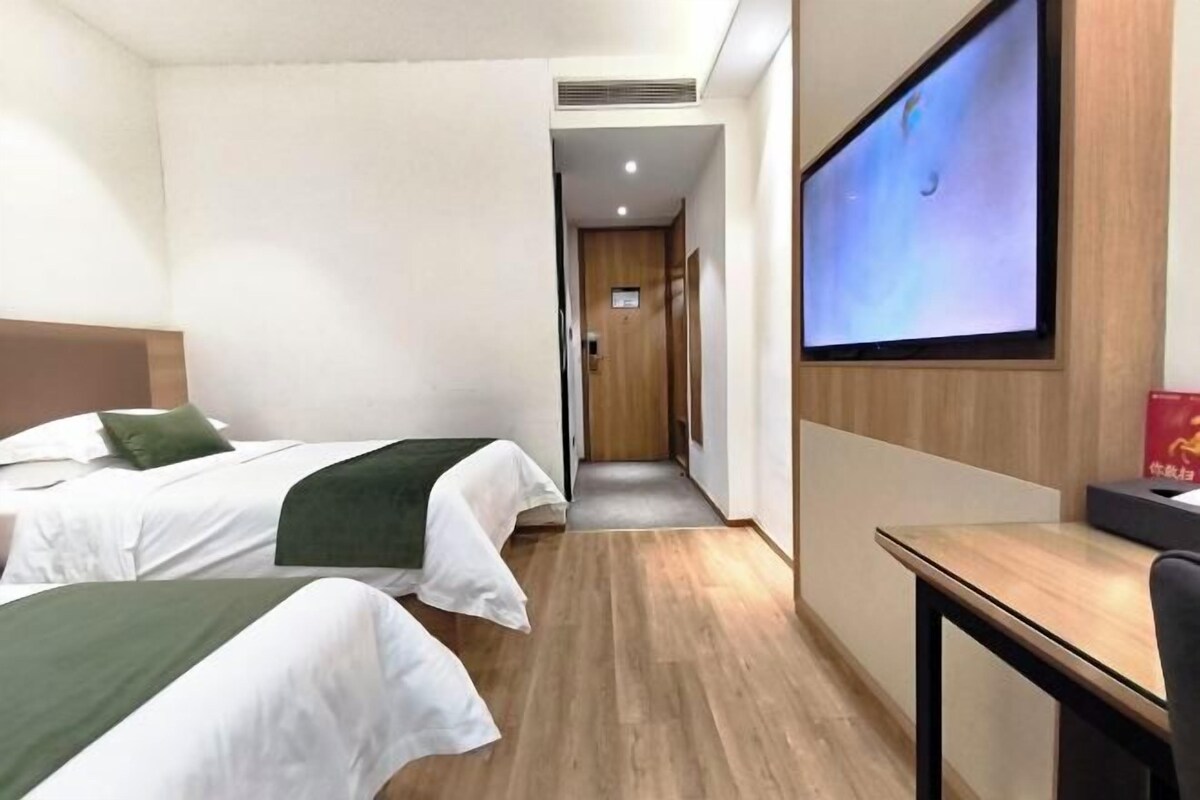 A hotel room with two beds, a TV, and a desk.
