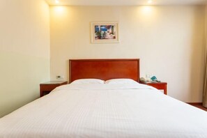 A hotel room with a large bed, a wooden headboard, two bedside tables, and a painting on the wall. - GreenTree Liaocheng Yanggu Huangshan Road Shizilou (Yanggu)