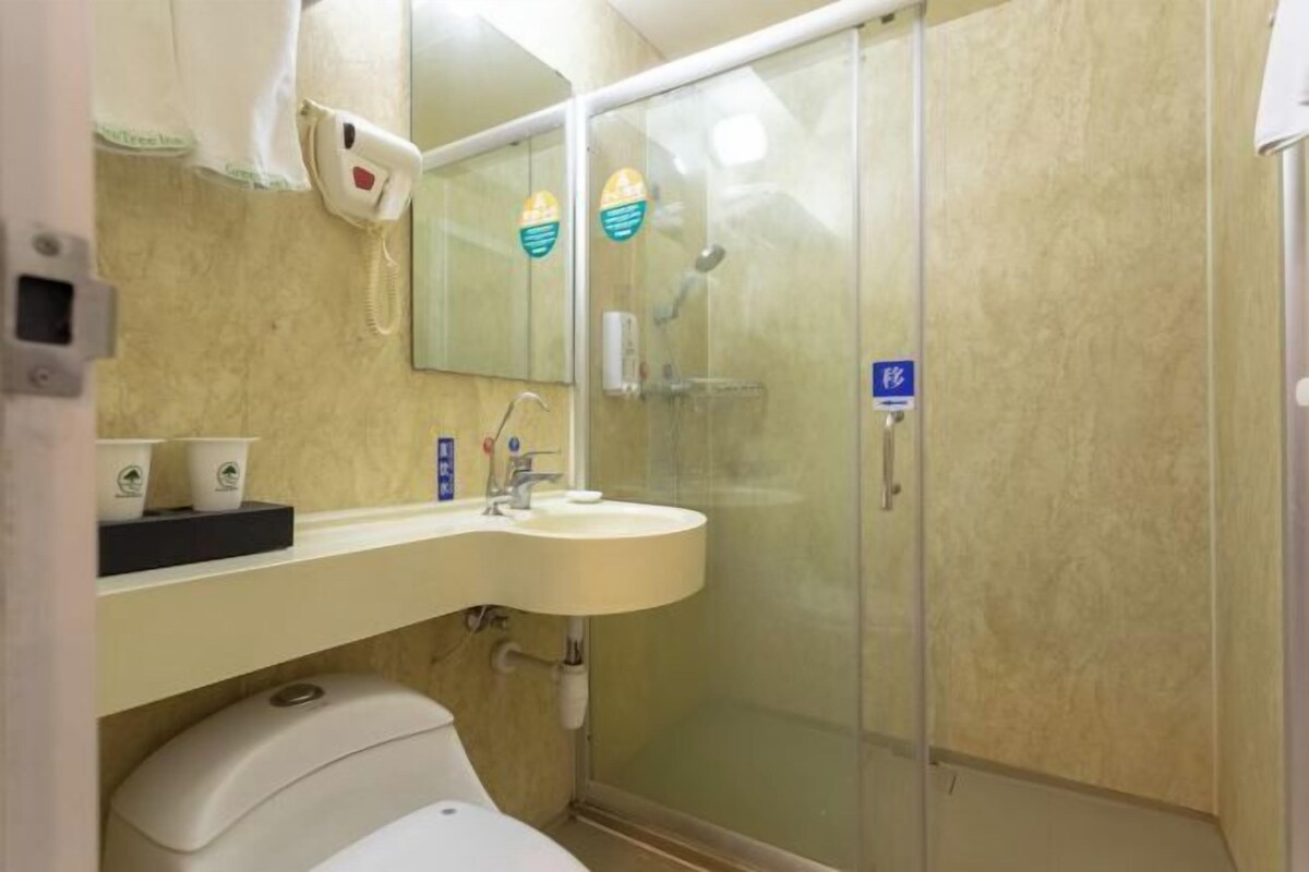 A bathroom with a toilet, sink, and glass shower enclosure.