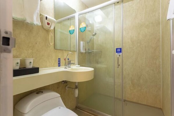 A bathroom with a toilet, sink, and glass shower enclosure.