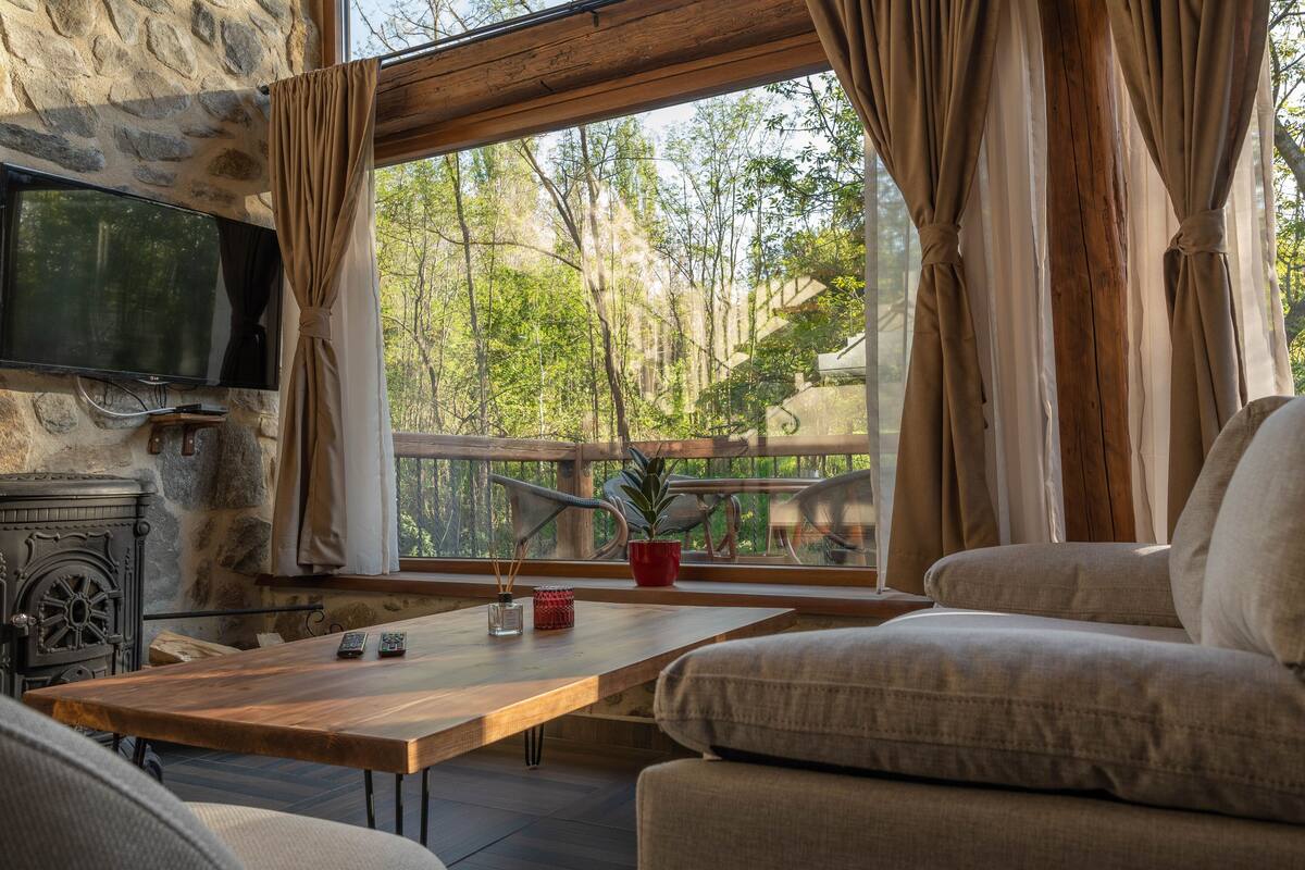 Ein gemütliches Wohnzimmer mit Kamin aus Stein, einem Holztisch und einer bequemen Couch.