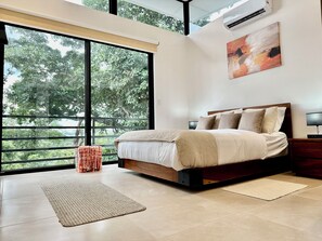 A modern bedroom with a large window, a bed with a wooden frame, a bedside table, and a painting on the wall.