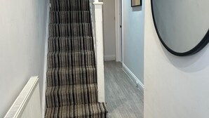 A staircase with striped carpet leading to a landing. - Tooting Stays (London)