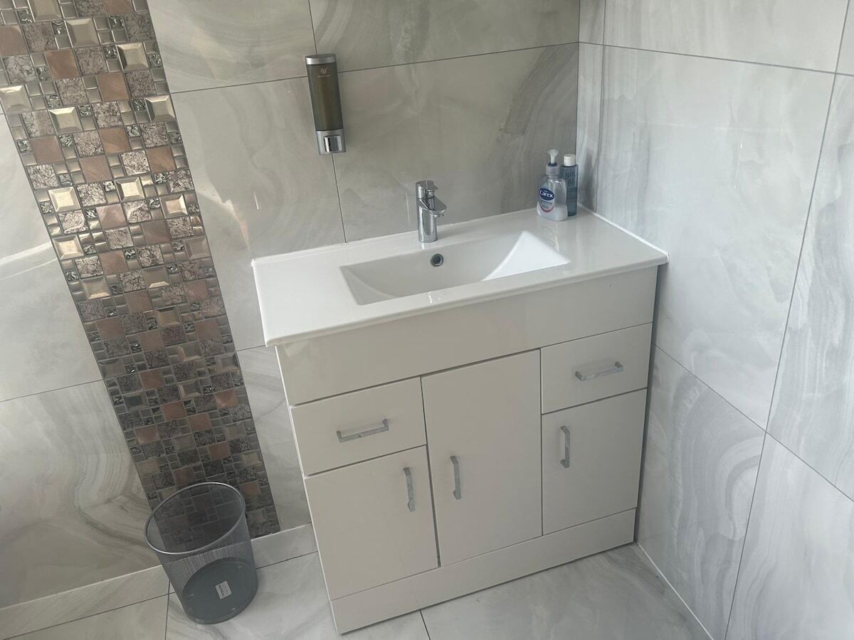 A bathroom with a white sink, a mirror, and a shower area.