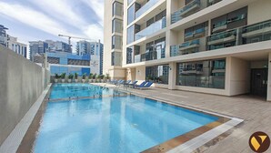 A modern hotel pool area with a clear view of the pool, sun loungers, and a construction crane in the background. - Vogue | Canal Bay close to Burj Khalifa Dubai Mall (Dubai)