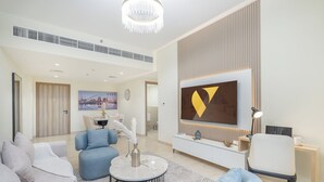 A modern living room with a sofa, armchairs, a coffee table, and a TV mounted on the wall. - Vogue | Canal Bay close to Burj Khalifa Dubai Mall (Dubai)
