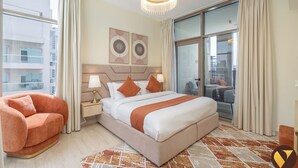 A modern hotel room with a large bed, a chaise lounge, a chandelier, and a city view. - Vogue | Canal Bay close to Burj Khalifa Dubai Mall (Dubai)