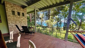 A covered outdoor area with a tiled floor, two lounge chairs, a small table, and a hammock. - Zen Zaru Beautiful Hidden Hotel (Quepos)