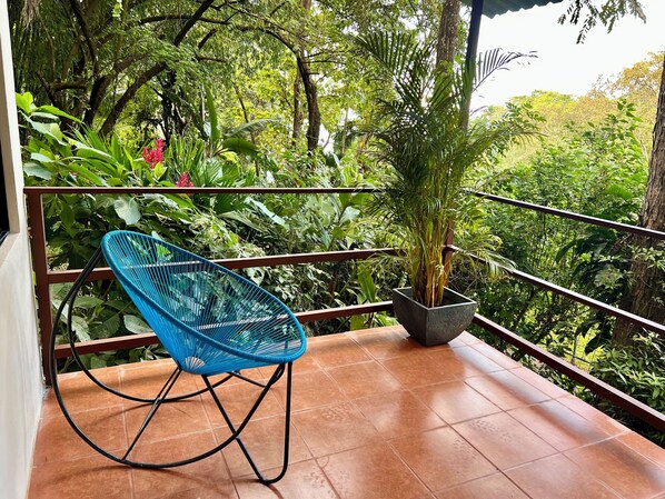A blue chair on a tiled balcony with a potted plant and lush greenery in the background. - Zen Zaru Beautiful Hidden Hotel (Quepos)