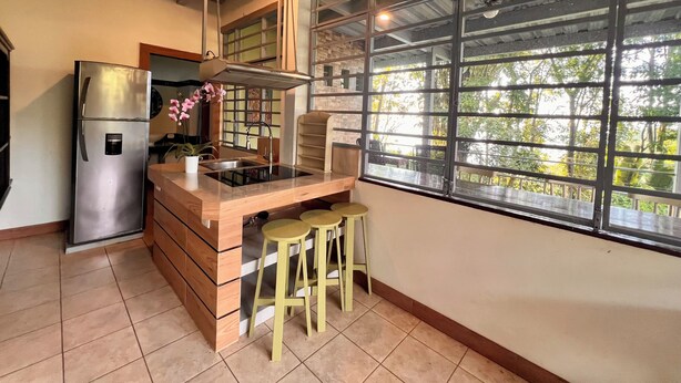 A kitchen with a stainless steel refrigerator, a built-in stove, and a window with a view of greenery. - Zen Zaru Beautiful Hidden Hotel (Quepos)