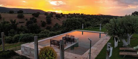 Una piscina al aire libre, sombrillas, sillones reclinables de piscina