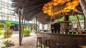 A bar area with a thatched roof, wooden counter, and stools. - Lux 2BR w/ Rooftop Pool+ Close to Beach (Tulum)