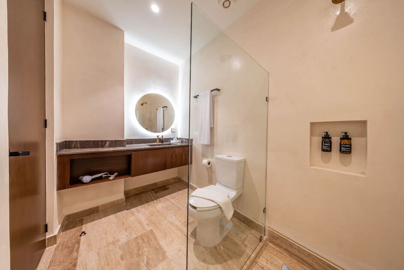 A modern bathroom with a glass shower enclosure, a marble-topped sink, and a toilet.