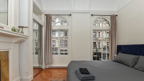 A bedroom with a large bed, a fireplace, and two windows with curtains.