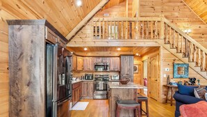 L’intérieur d’une cabane en bois comprend une cuisine, un coin repas et un escalier.