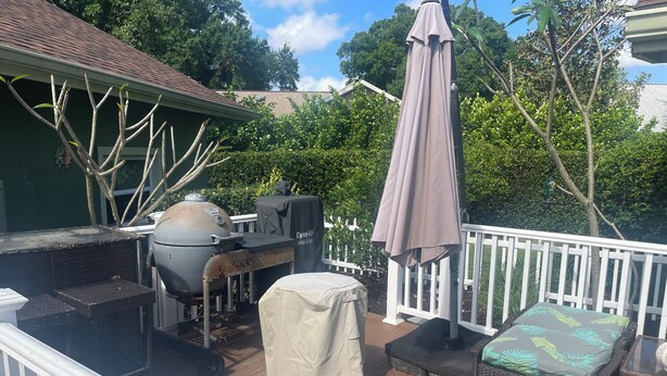 A deck with a grill, covered seating, and a white railing. - Charming studio in superb Fort Myers that’s conveniently located (Fort Myers)