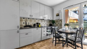 Eine moderne Küche mit weißen Schränken, einer Backspülwand im Fischgrätmuster und einem Holzboden.