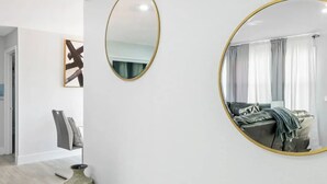 A modern living room with a large round mirror, a minimalist sofa, and two decorative vases. - 4-bedroom house in charming Riviera Beach with WiFi, AC. Relax and unwind (RIVIERA BEACH)