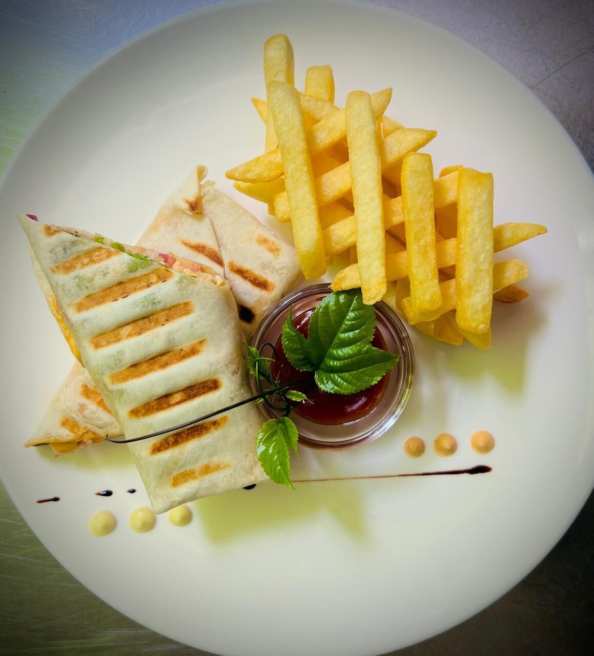 A plate with a sandwich, French fries, and a small bowl of sauce.