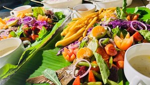 A table with various dishes, including salads, fruits, and French fries, served on banana leaves. - BAGEECHAA STAY (Dharavandhoo)