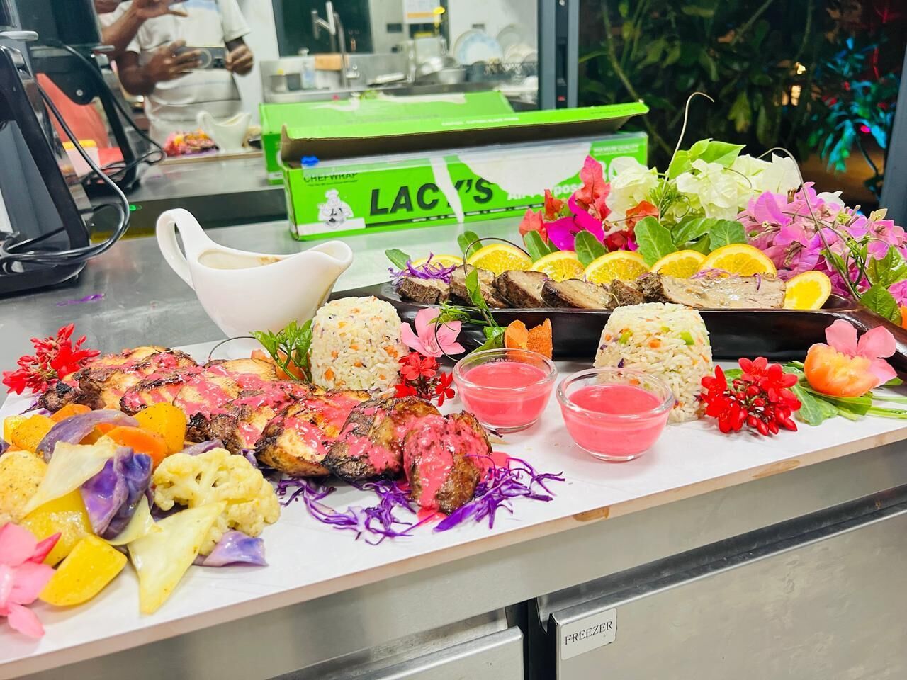 A buffet table with various dishes, including grilled meat, rice, and colorful vegetables.