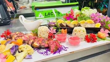 A buffet table with various dishes, including grilled meat, rice, and colorful vegetables.