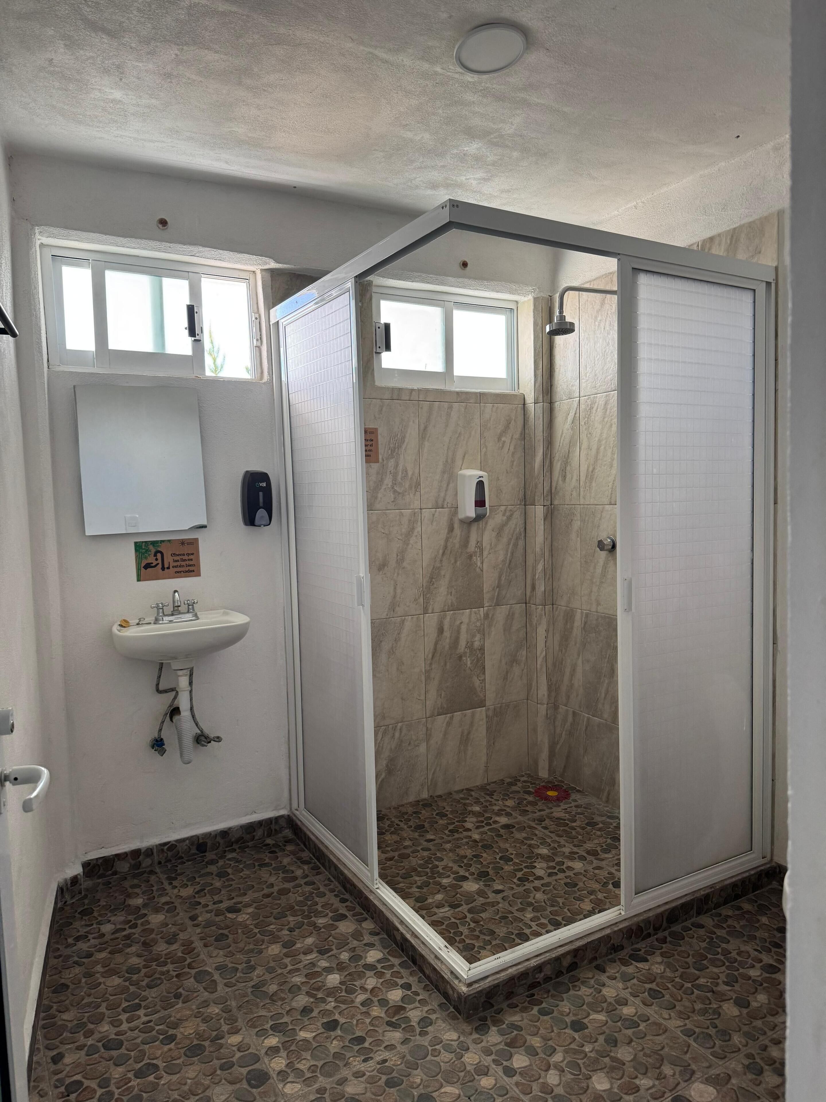 A bathroom with a shower, sink, and a tiled floor.