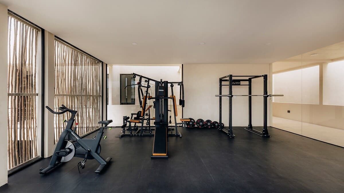 Ein Fitnessraum mit Trainingsgeräten, einem Ergometer und einer Gewichtbank.