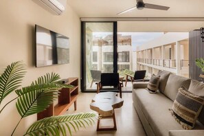 A modern living room with a sofa, chairs, a coffee table, and large windows.