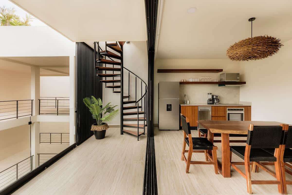 Un apartamento moderno con una escalera, un comedor y una cocina.
