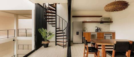 Un apartamento moderno con una escalera, un comedor y una cocina.