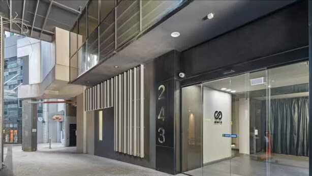 Un bâtiment moderne doté d’une façade en verre, de portes numérotées et d’une sortie de secours bien visible.