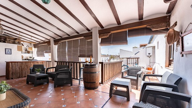 Un espace extérieur abrité, doté de mobilier en osier, d’un bar en bois et offrant une vue sur le paysage urbain.