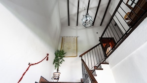 Un escalier avec une main courante en bois et des balustres en métal noir, une lanterne suspendue et une plante en pot.