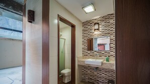 Een badkamer met betegelde vloer, toilet, wastafel en spiegel.